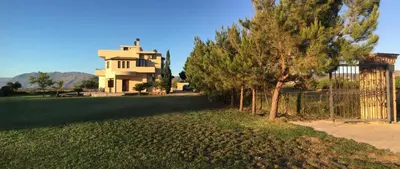 a house with a fence and trees in front of a yard at Villa Allegra in Korfalónas