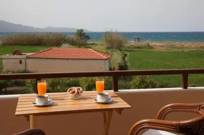 a table on a balcony with two cups of orange juice at Villa Allegra in Korfalónas