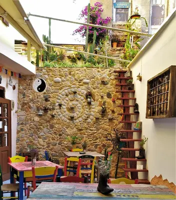 a room with a stone wall and tables and chairs at Poco Loco Bed & Breakfast in Chania Town