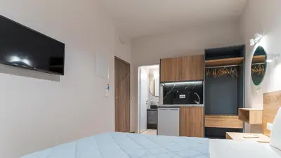 a white room with a bed and a kitchen at Nicole Rooms in Palaiochóra