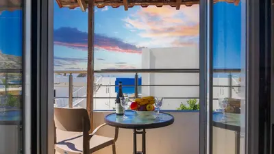 a table on a balcony with a view of the ocean at Nicole Rooms in Palaiochóra