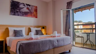 a bedroom with two beds and a balcony at Nicole Rooms in Palaiochóra