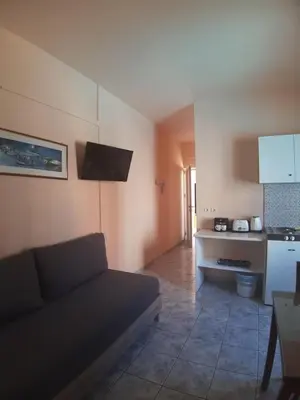 a living room with a couch and a kitchen at Eden Beach Hotel in Agia Marina Nea Kydonias
