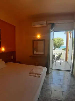 a bedroom with a bed and a view of a patio at Eden Beach Hotel in Agia Marina Nea Kydonias
