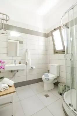 a white bathroom with a toilet and a sink at Castell Hotel in Kissamos