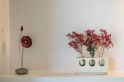 a white vase with flowers on a shelf with a flower at Blue Sea Luxury Villa in Maleme