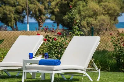 two white chairs and a table in the grass at Blue Sea Luxury Villa in Maleme