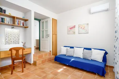 a living room with a blue couch and a desk at Stone Built Private villa Emerald with pool, 30m to Beach & BBQ! in Ropanianá