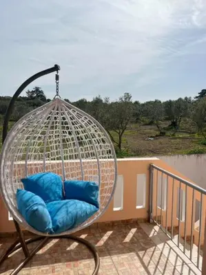 a hanging chair with blue pillows on a balcony at Angellinas Apartments in Kato Daratso