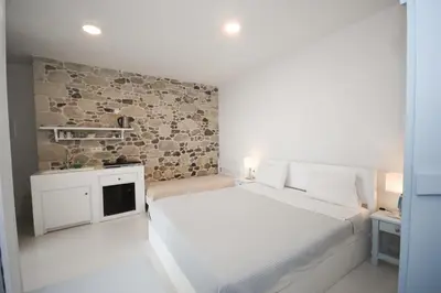 a bedroom with a white bed and a stone wall at Elia in Kavoúsion