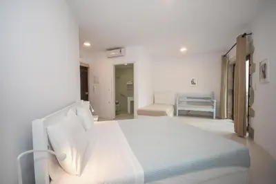 a white bedroom with a white bed and a bathroom at Elia in Kavoúsion