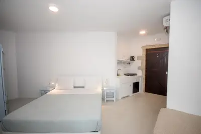 a white bedroom with a bed and a kitchen at Elia in Kavoúsion
