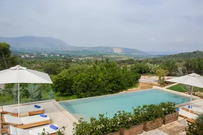 a swimming pool with chairs and umbrellas next to at Aoria Villa By Hope Estate in Arménoi