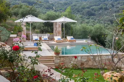 a pool with chairs and umbrellas in a garden at Aoria Villa By Hope Estate in Arménoi