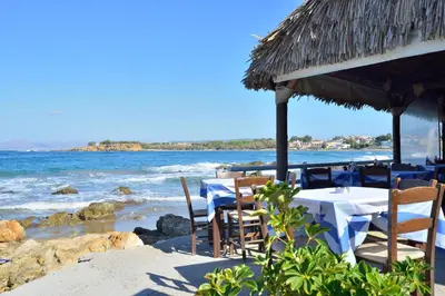 a restaurant with tables and chairs on the beach at Kalamaki Apartments in Kalamaki Chanion