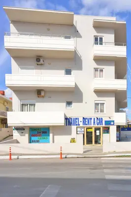a white building with a sign that reads travel rent a car at Kalamaki Apartments in Kalamaki Chanion