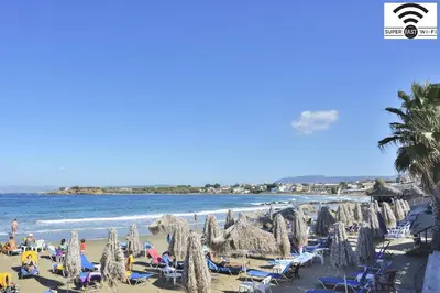 a beach with umbrellas and chairs and the ocean at Kalamaki Apartments in Kalamaki Chanion