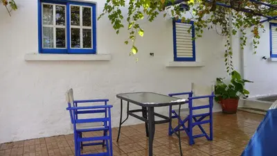 a table and two blue chairs in front of a building at Iliana's Bungalow in Arménoi