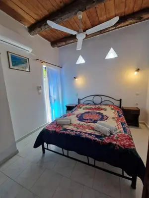 a bedroom with a bed and a ceiling fan at Iliana's Bungalow in Arménoi