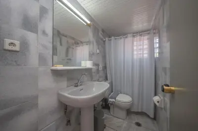 a white bathroom with a sink and a toilet at Manias Hotel Apartments in Agia Marina Nea Kydonias