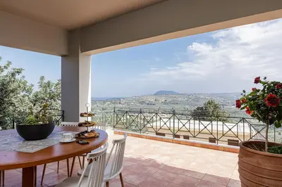 a balcony with a table and chairs and a view at Villa Staride, sea view, private heated pool, playground in Païdhokhórion