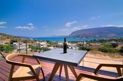 a table with a wine bottle and two chairs on a balcony at Seametry Luxury Living Apartments ADULTS ONLY in Souda