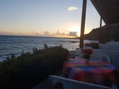 a table on a balcony with a view of the ocean at Taverna Akrogiali in Loutro