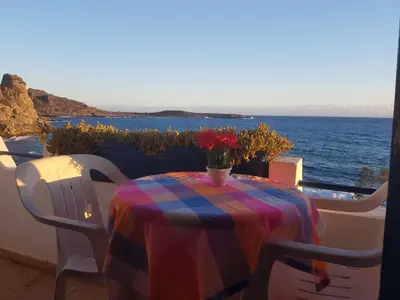 a table with a colorful table cloth on a balcony with the ocean at Taverna Akrogiali in Loutro