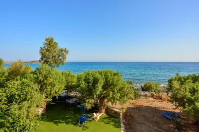 a view of the beach with chairs and trees at Taverna Akrogiali in Loutro