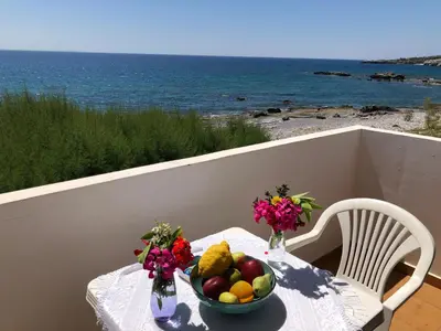 a table with a bowl of fruit and flowers on it at Taverna Akrogiali in Loutro