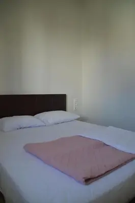 a white bed with a pink blanket on it at Christini Apartment in Chania Town