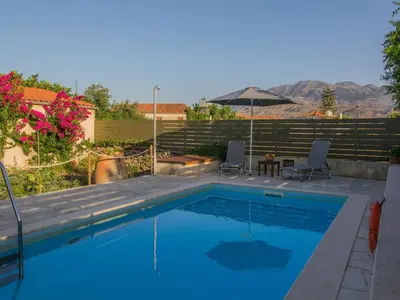 a swimming pool with two chairs and a table at Villa in Crete with Vineyard Experience in Kalamítsion Alexándrou