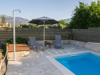 a pool with two chairs and a table and an umbrella at Villa in Crete with Vineyard Experience in Kalamítsion Alexándrou