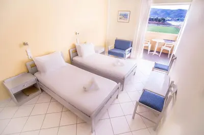 a room with two beds and a table and chairs at Galini Beach Hotel in Kissamos
