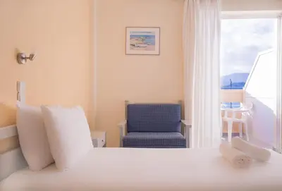 a bedroom with a bed and a blue chair at Galini Beach Hotel in Kissamos