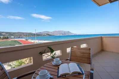 a balcony with a table and chairs with a view of the ocean at Galini Beach Hotel in Kissamos