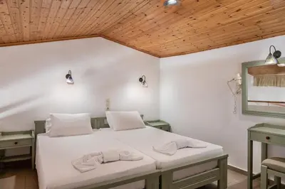 a bedroom with a bed with white sheets and wooden ceilings at Androulakis Apartments in Gerani Chanion