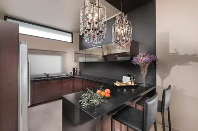 a kitchen with a black counter and chandeliers at Golden View Villa in Kato Daratso
