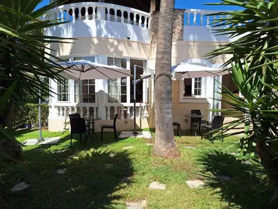 a building with chairs and umbrellas in front of it at Perla Beach in Agia Marina Nea Kydonias