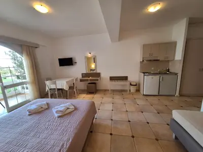 a bedroom with a bed and a table and a kitchen at Perla Beach in Agia Marina Nea Kydonias