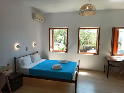 a bedroom with a bed and a desk and two windows at Imeros in Chania Town