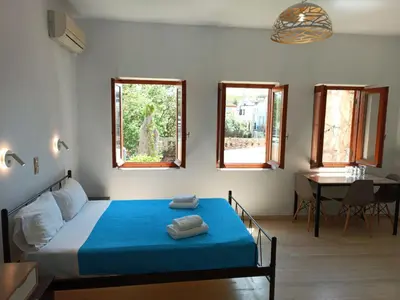 a bedroom with a bed and a table and windows at Imeros in Chania Town