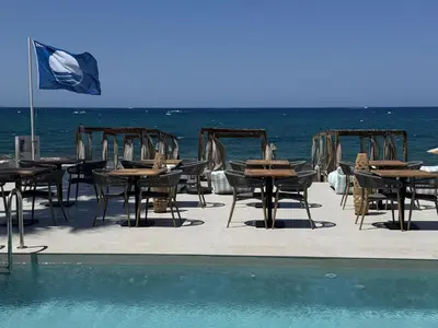 a group of tables and chairs next to the ocean at Τhe Noverian Antama Organic Beach Resort Chania with Outdoor Heated Pool in Agia Marina Nea Kydonias