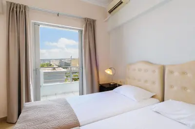 a bedroom with two beds and a large window at Archontiki City Hotel in Chania Town