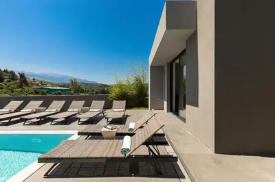 a swimming pool with lounge chairs next to a house at Elea Villas - Aspro & Blanche in Almirida
