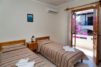a bedroom with two beds and a door to a balcony at Villa Alexander in Kalathas
