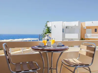a table with two chairs on a balcony with the ocean at Villa Alexander in Kalathas