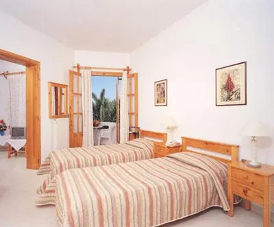 a bedroom with two beds and a table and a window at Villa Alexander in Kalathas