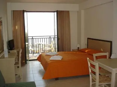 a bedroom with a large orange bed and a balcony at Margarita Beach Hotel in Agia Marina Nea Kydonias