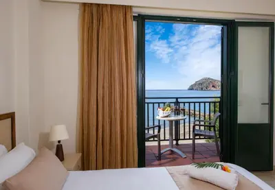 a bedroom with a bed and a view of the ocean at Margarita Beach Hotel in Agia Marina Nea Kydonias